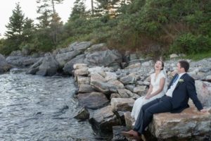 Couple sitting on rocks next to the bay in the Town of Boothbay Harbor