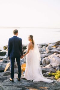 Bride and Groom standing on rocky shore.